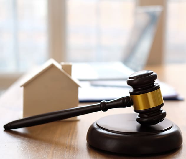 A wooden gavel beside a small house depicting property law.